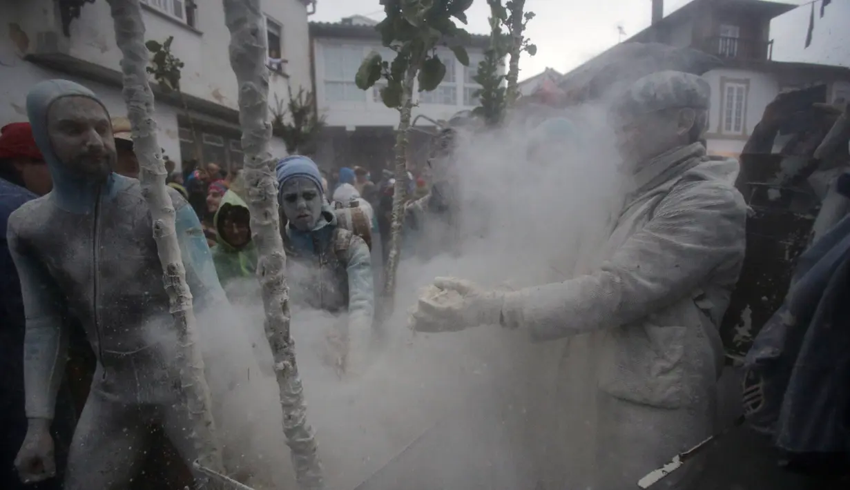 Seorang peserta (kanan) dilempari tepung selama berlangsungnya Festival O Entroido di Laza, Spanyol, Senin (8/2). Festival yang berlangsung selama seminggu itu dianggap sebagai peristiwa sosial dan budaya utama di kota Laza. (REUTERS/ Miguel Vidal)
