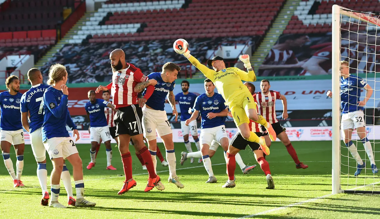 Kiper Everton, Jordan Pickford, berusaha menepis bola saat menghadapi Sheffield United pada laga lanjutan Premier League di Bramall Lane Stadium, Selasa (21/7/2020) dini hari WIB. Everton menang 1-0 atas Sheffield United. (AFP/Peter Powell/pool)