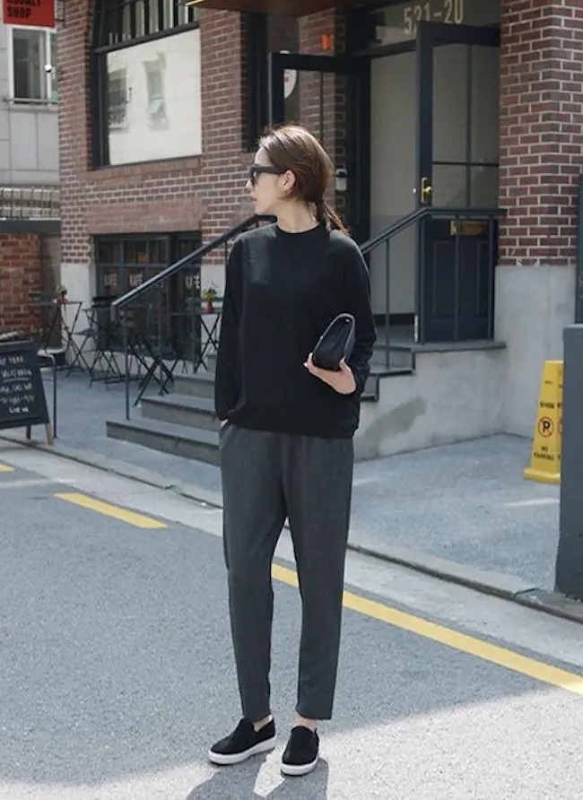 Sweater hitam dipadukan bersama tailored trousers warna abu-abu dan pakai slip on, penampilan seperti ini memberi kesan simple. (sumber foto: Bloglovin'/Pinterest)
