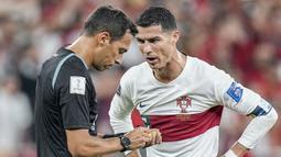 Megabintang Portugal, Crsitiano Ronaldo, berbincang dengan wasit Facundo Tello saat melawan Maroko pada laga babak perempat final Piala Dunia 2022 di Al Thumama Stadium, Sabtu (10/12/2022). (AP/Ariel Schalit)