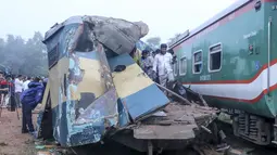 Orang-orang berdiri di gerbong kereta yang rusak parah setelah dua kereta yang melaju bertabrakan di distrik Brahmanbaria, 82 kilometer (51 mil) timur ibukota, Dhaka, Bangladesh, Selasa (12/11/2019). Sekitar 16 orang tewas dan 60 lainnya terluka akibat kecelakaan tersebut. (AFP Photo/STR)