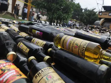 Alat berat menggilas ribuan botol minuman keras  (miras) hasil sitaan polisi di halaman Polres Bogor, Cibinong, Kamis (17/5). Miras yang dimusnahkan lebih dari 32 ribu botol, baik lokal maupun impor dengan beragam merek. (Merdeka.com/Arie Basuki)