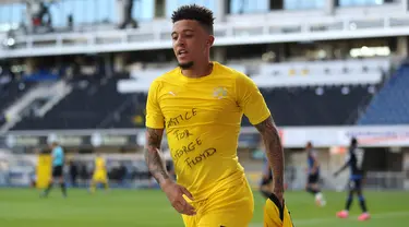 Gelandang Borrusia Dortmund, Jadon Sancho berselebrasi menunjukkan tulisan di kaos dalam 'Justice for George Floyd' usai mencetak gol ke gawang SC Paderborn 07 di Benteler Arena di Paderborn, Jerman (1/6/2020). Dalam pertandingan ini Dortmund menang telak 6-1 atas Paderborn. (Lars Baron/Pool via AP)