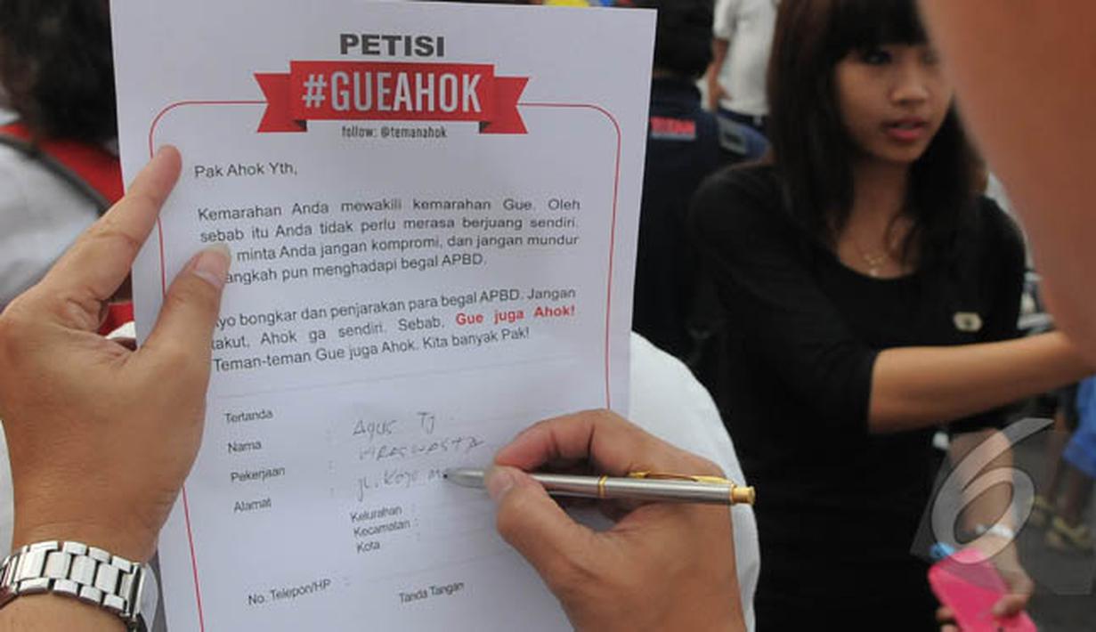 Seorang warga menulis petisi mendukung Gubernur Ahok di Bundaran HI, Jakarta, Minggu (1/3/2015). Aksi mereka sebagai bentuk dukungan kepada Ahok yangingin membongkar dana siluman di Pemprov DKI (Liputan6.com/Herman Zakharia)