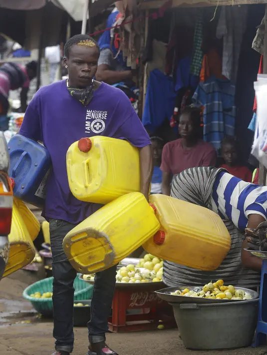 Seorang pria membawa wadah plastik kosong di pasar Kaporo di Conakry, Guinea, Senin (13/9/2021). Pasukan elit militer Guinea melakukan kudeta dan menangkap Presiden Alpha Conde pada Minggu, 5 September lalu. (AP Photo/ Sunday Alamba)