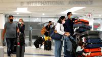 Wisatawan keluar dari pintu kedatangan Internasional di Bandara Miami, Florida, Senin (20/9/2021). Amerika Serikat akan mencabut larangan perjalanan covid-19 pada semua penumpang udara yang sudah divaksin lengkap dan menjalani tes serta pelacakan kontak pada November. (Joe Raedle/Getty Images/AFP)