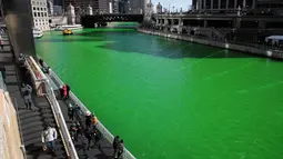 Wisatawan memandangi sungai Chicago di Illinois, AS yang berubah warna menjadi hijau, 11 Maret 2017. Hijaunya warna sungai tersebut sebenarnya berasal dari cairan pewarna khusus untuk perayaan St. Patrick's Day (SCOTT OLSON/GETTY IMAGES NORTH AMERICA/AFP)