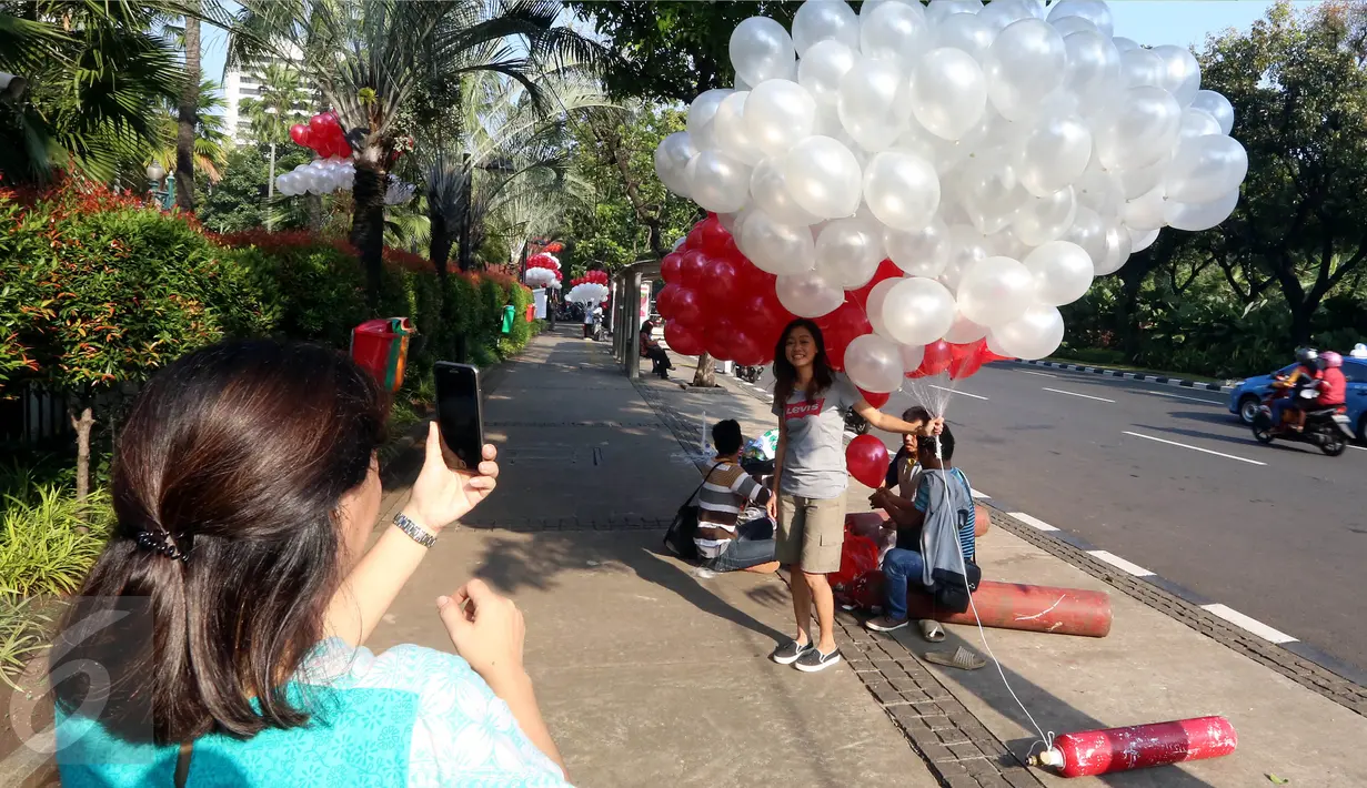 Warga berfoto dengan balon merah putih di halaman Balai Kota DKI Jakarta, Selasa (9/5). Ada yang berbeda pagi ini, Gubernur DKI Basuki Tjahaja Purnama (Ahok) tidak ke Balai Kota terlebih dulu menjelang sidang pembacaan putusan. (Liputan6.com/Johan Tallo)