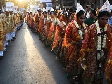 Iring-iringan calon pasangan pengantin di India saat mengikuti upacara pernikahan massal di Kolkata (14/2). Lebih dari 160 pasangan yang mengalami kesulitan ekonomi mengikuti acara nikah massal tersebut. (AFP Photo/Dibyangshu Sarkar)