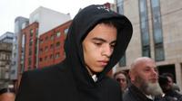 Mason Greenwood mengenakan jas hitam dan kemeja putih di dalamnya sambil menunduk untuk hadir ke persidangan secara singkat.