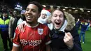 Pemain Bristol City, Korey Smith dan fans merayakan gol ke gawang Manchester United pada perempat final Piala Liga Inggris di Ashton Gate, Kamis (21/12). Klub kasta kedua Bristol City sukses menyingkirkan Manchester United 2-1. (Nick Potts/PA via AP)