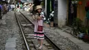 Foto pada 8 Juni 2019 memperlihatkan seorang wanita berswafoto di tengah jalur kereta api populer di Hanoi, Vietnam. Turis sengaja datang ke Old Quarter untuk berfoto di rel kereta api yang dianggap ' instagramable' tersebut. (Photo by Manan VATSYAYANA / AFP)