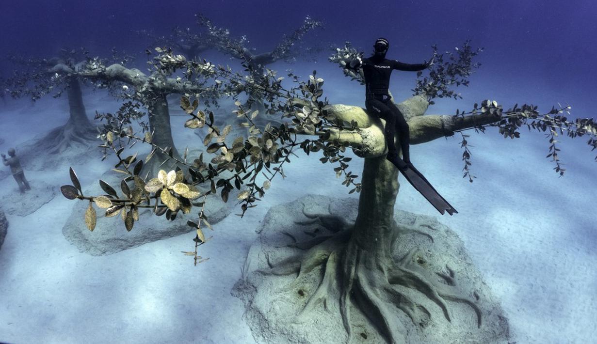 Penyelam bebas Angels Savvas duduk di atas pohon pahatan di taman patung bawah laut MUSAM, Ayia Napa, Siprus, 18 September 2021. Taman ini menggunakan semen netral pH yang memfasilitasi pertumbuhan karang. (EMILY IRVING-SWIFT/AFP)