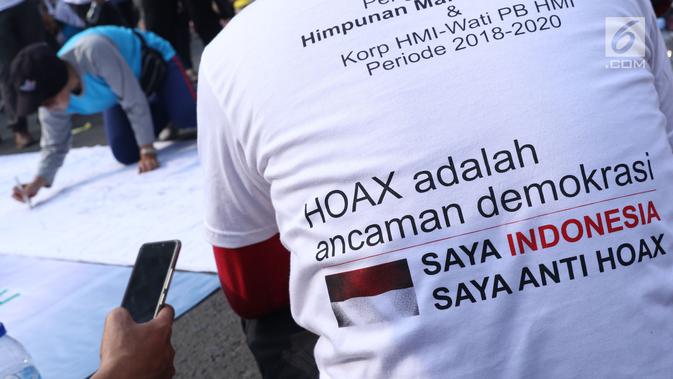 Salah satu pengurus PB HMI melihat warga yang menandatangani spanduk dukungan anti hoax di kawasan Bundaran Hotel Indonesia, Jakarta, Minggu (18/11). PB HMI mensosialisasikan Hoax sebagai ancaman demokrasi di Indonesia. (Liputan6.com/Helmi Fithriansyah)