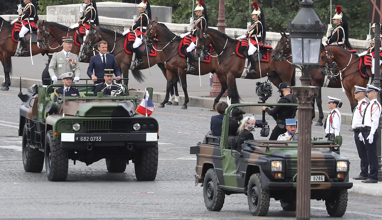 Presiden Prancis Emmanuel Macron (kanan) tiba dengan Kepala Staf Pertahanan Jenderal Francois Lecointre dalam upacara militer Bastille Day di Place de la Concorde di Paris, Prancis (14/7/2020). (AFP/Thomas Samson)