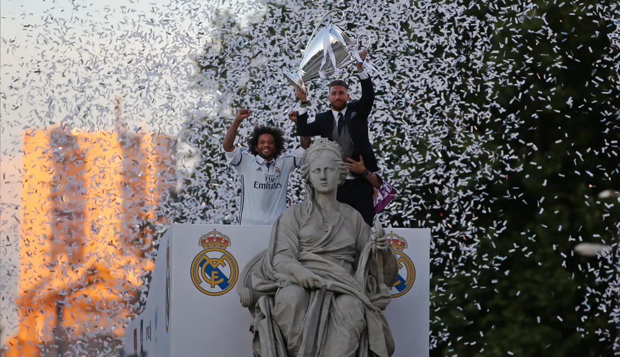 Bek Real Madrid Sergio Ramos dan Marcelo mengangkat trofi Liga Champions di dekat patung Cibeles saat merayakan kemenangan setelah meraih gelar ke-12 di Madrid, Spanyol (4/6). (AP Photo / Paul White)