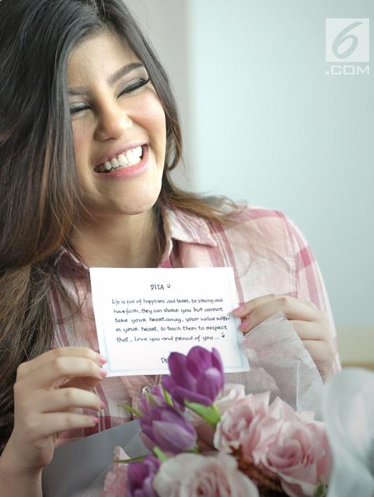 Memegang bunga dari Denny.ekspresi Dita pun juga aterlihat begitu bahagia ketika membacakan isi surat kecil yang bertuliskan kalimat romantis berbahasa Inggris tersebut. (Bambang E. Ros/Fimela)