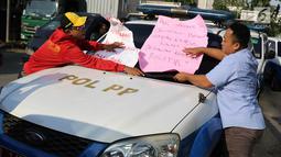 Karyawan Hotel Alexis menempelkan poster tuntutan di mobil Satpol PP saat unjuk rasa di Jakarta Utara, Kamis (29/3). Penutupan terkait kasus dugaan adanya praktek prostitusi dan perdagangan manusia di hotel tersebut. (Liputan6.com/Immanuel Antonius)