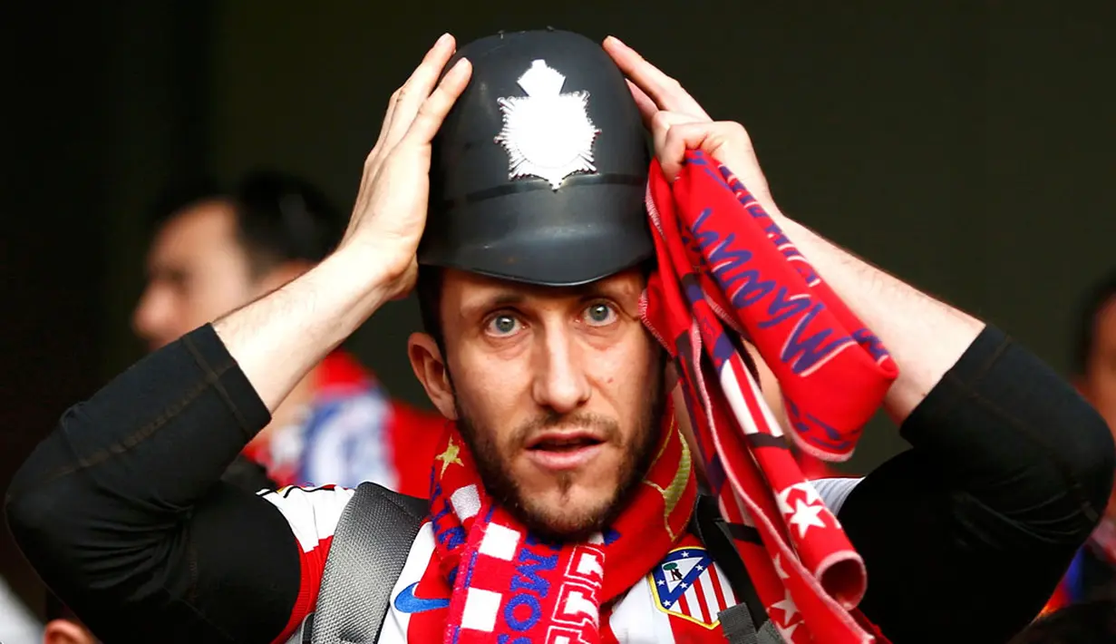 Salah satu fans Atletico Madrid terlihat memakai replika helm polisi tradisional Inggris saat menyaksikan laga semifinal kedua Liga Champions, Stamford Bridge, London (1/5/02014). (REUTERS/Eddie Keogh)