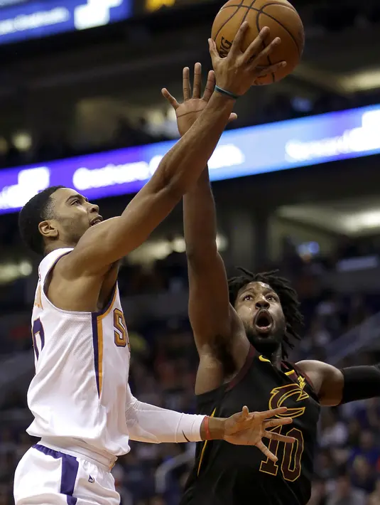 Pebasket Cleveland Cavaliers, John Holland, berebut bola dengan pebasket Phoenix Suns, Troy Daniels, pada laga NBA di Talking Stick Resort Arena, Rabu (14/3/2018). Cleveland Cavaliers menang 129-107 atas Phoenix Suns. (AP/Rick Scuteri)