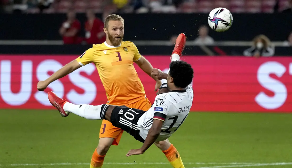 Gelandang Jerman, Serge Gnabry berebut bola dengan pemain Armenia, Varazdat Haroyan pada pertandingan grup J Kualifikasi Piala Dunia 2022 di stadion Mercedes-Benz Arena di Stuttgart, Jerman, Senin (6/9/2021). Jerman atas Armenia 6-0. (AP Photo/Matthias Schrader)