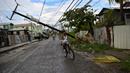 Orang-orang bersepeda di jalan dengan tiang listrik tumbang setelah Badai Lisa di Belize City, Belize, 3 November 2022. Badai Tropis Lisa menyebabkan banjir dan membuat sebagian negara itu menjadi gelap gulita. (Johan ORDONEZ/AFP)