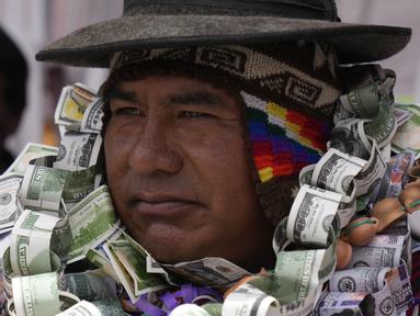 Seseorang berpakaian seperti Ekeko, Dewa Kemakmuran, diselimuti uang palsu pada hari pembukaan Pameran Alasita tahunan, di mana Ekeko adalah tokoh utamanya di El Alto, Bolivia, Selasa (24/1/2023). Orang-orang membeli replika kecil dari hal-hal yang ingin mereka peroleh sepanjang tahun, seperti rumah, mobil, dan kekayaan. Kata Aymara "Alasita" berarti "belikan aku". (AP Photo/Juan Karita)