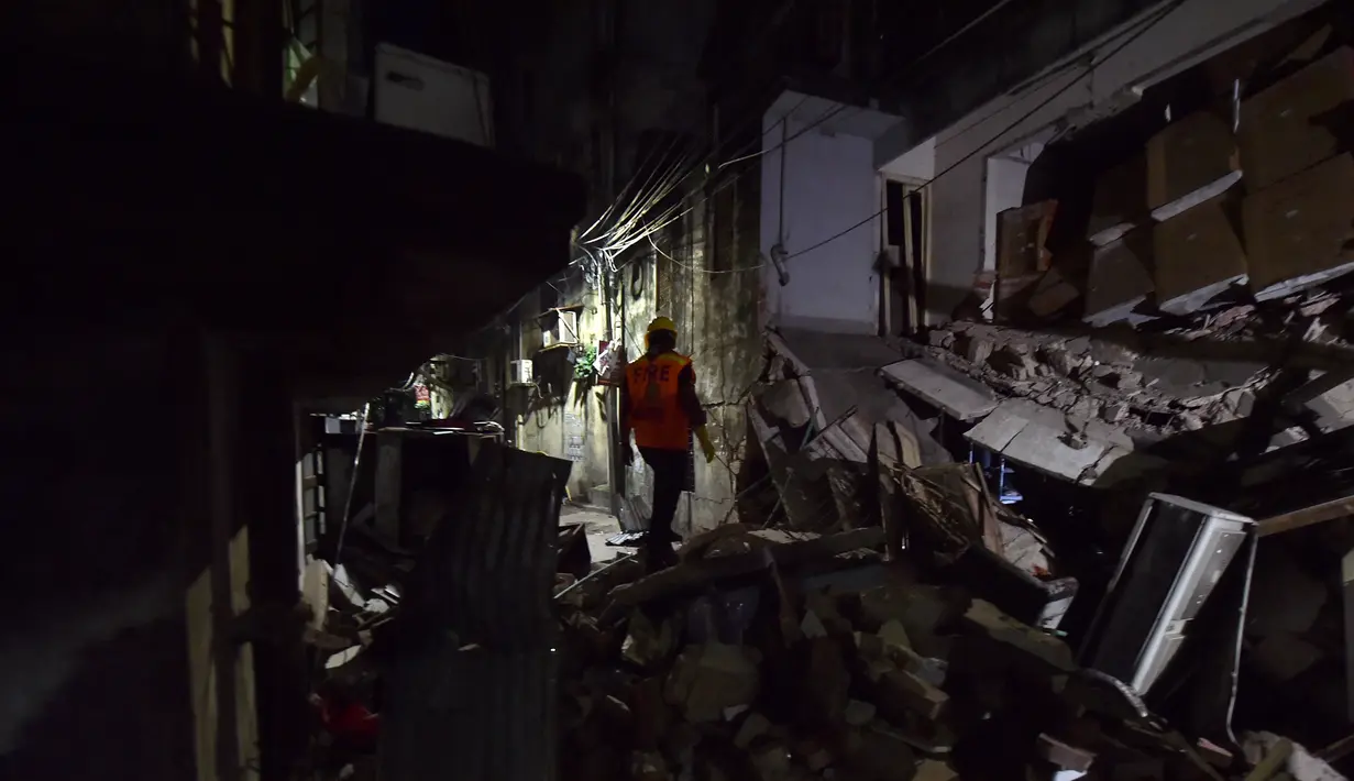 Petugas pemdam kebakaran memeriksa tempat kejadian setelah dugaan ledakan gas di jalanan ramai di Moghbazar, Dhaka, Bangladesh, Minggu (27/6/2021). Tayangan televisi memperlihatkan pilar-pilar yang rubuh, beton pecah dan pecahan kaca berserakan di seberang jalan. (Munir Uz zaman/AFP)