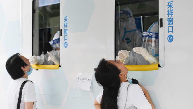 Petugas medis mengambil sampel usap tenggorokan sejumlah warga dari sebuah kendaraan tes mobile yang baru diadopsi di Distrik Xicheng, Beijing, China, Minggu (28/6/2020). (Xinhua/Ju Huanzong)