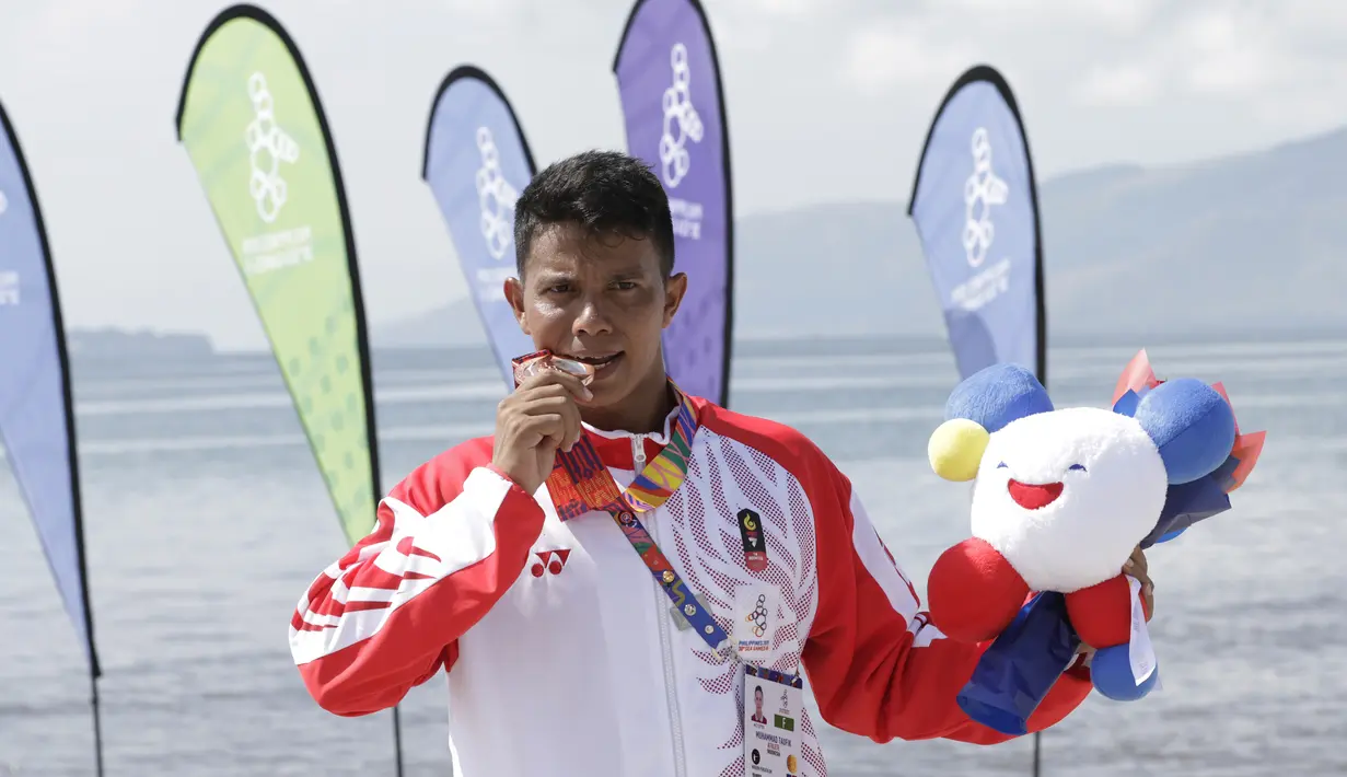 Atlet modern pentathlon, Muhammad Taufik, menunjukan medali usai meraih perunggu pada nomor beach triathle individual SEA Games 2019 di Subic, Jumat (6/12). Dirinya membukukan catatan waktu 00:17:37.76.  (Bola.com/M Iqbal Ichsan)