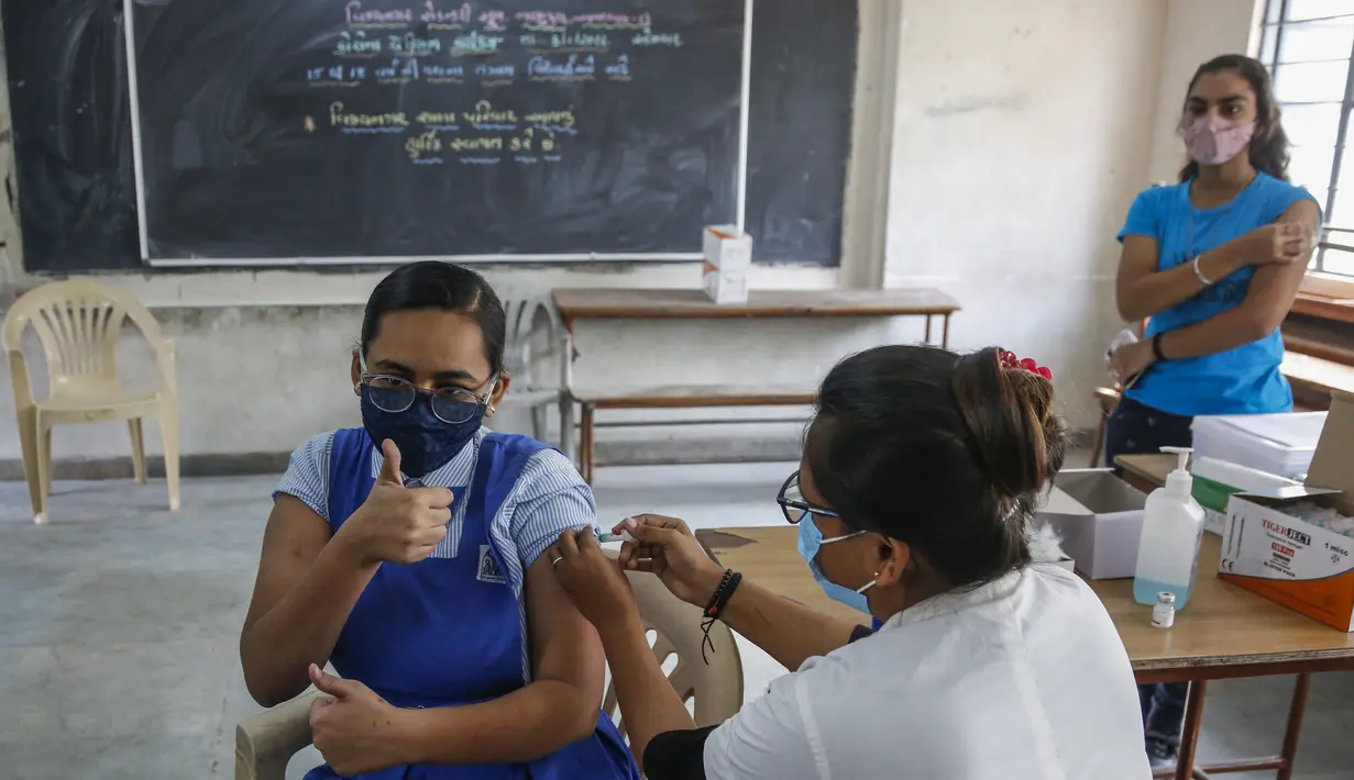 Petugas medis memberikan vaksin COVID-19 kepada seorang siswa di sebuah sekolah di Ahmedabad, Senin (3/1/2022). India mulai memvaksinasi remaja 15-18 tahun saat banyak negara bagian memberlakukan pembatasan ketat untuk menahan lonjakan infeksi yang dipicu oleh varian omicron. (AP Photo/Ajit Solanki)