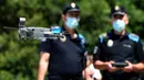 Polisi setempat menerbangkan sebuah drone atau pesawat tak berawak memperingatkan orang-orang untuk menjaga jarak di pantai Areas di Sanxenxo, Spanyol, Selasa (14/7/2020). Drone tersebut untuk memantau jaga jarak antarwisatawan saat berlibur di masa pandemi Corona. (MIGUEL RIOPA / AFP)
