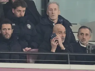 Pelatih Manchester City, Pep Guardiola, memberikan arahan melalui telpon dari tribun penonton saat anak asuhnya bermain imbang 1-1 melawan West Ham United pada pekan ke-30 Premier League 2025/2026 di London Stadium pada Minggu (15/3/2026). (AP Photo/Dave Shopland)