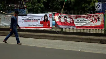 Pejalan kaki berjalan di depan spanduk partai politik yang terpampang di Jalan Sultan Agung, Manggarai, Jakarta, Selasa (16/1). Memasuki 2018, parpol berlomba mengambil hati rakyat dengan berbagai janji terpampang di spanduknya. (Liputan6.com/JohanTallo)