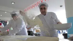 Peserta mempersiapkan adonan untuk roti manousheh raksasa di Choueifat, Beirut, Lebanon (22/11). Roti terpanjang di dunia sebelumnya dipegang oleh Arab Saudi pada 2014 dan diukur 15,17 meter. (AFP PHOTO/STR)