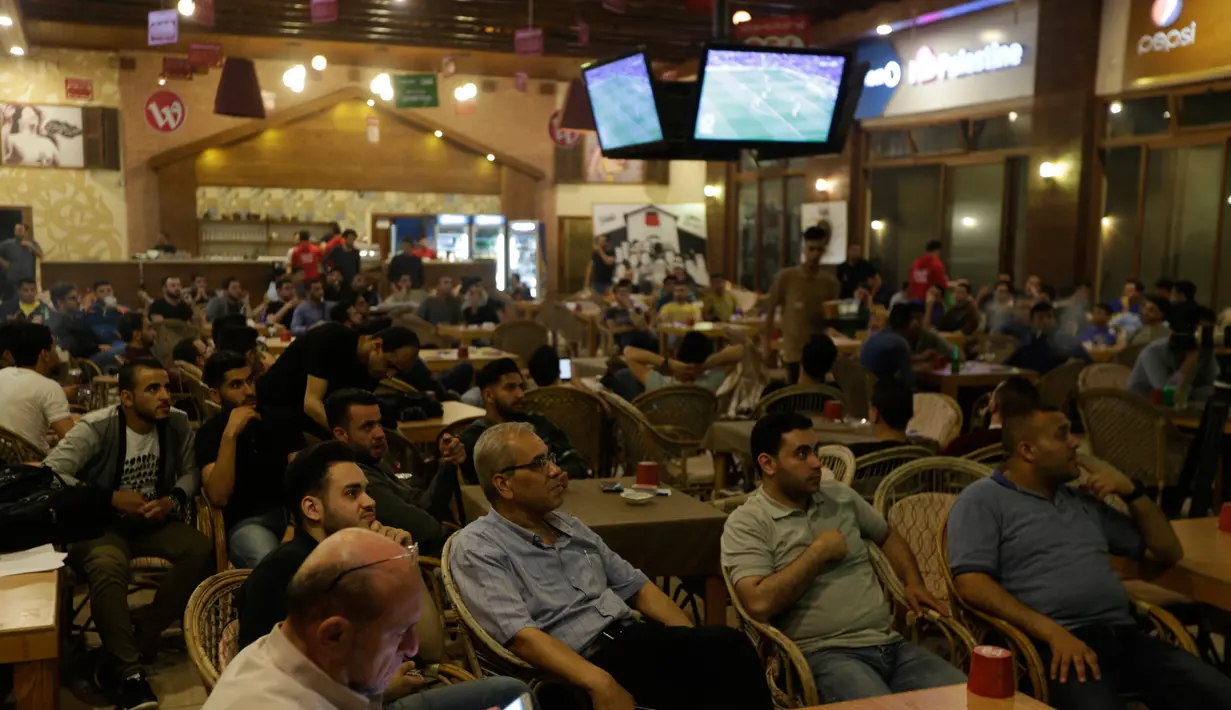 Warga Palestina menyaksikan pertandingan sepak bola Clasico antara Real Madrid dan Barcelona FC di sebuah kafe di Kota Gaza (6/5). Sebelum pertandingan ini, Barcelona telah memastikan gelar juara La Liga yang ke 25. (AFP Photo/Mahmud Hams)