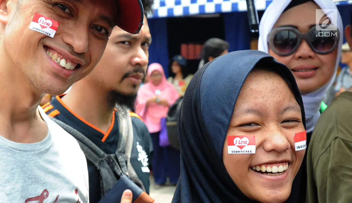 Calon penonton menghiasi muka dengan stiker bendera merah putih saat antre di sepanjang pendestrian Senayan untuk mengikuti Closing Ceremony Asian Games 2018, di Stadion GBK, Jakarta, Minggu (2/9). (merdeka.com/Arie Basuki)