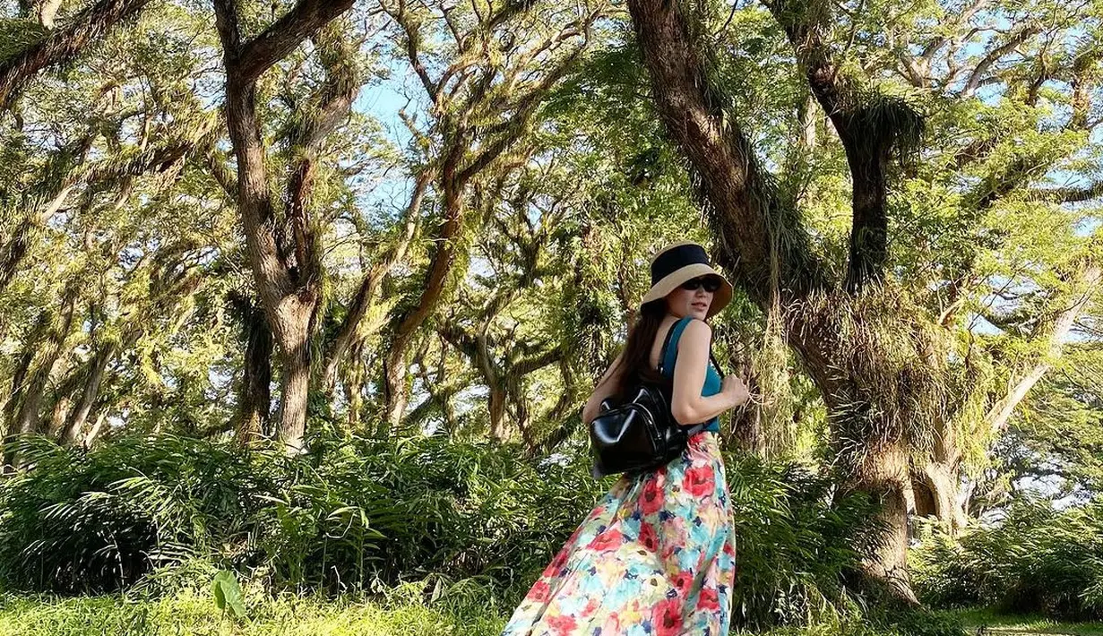 Manisnya penampilan Ayu Ting Ting saat liburan di daerah tropis. Ia mengenakan tank top hijau, yang dipadunya dengan midi skirt bercorak flora wawrna-warni. [Foto: Instagram/ayutingting92]