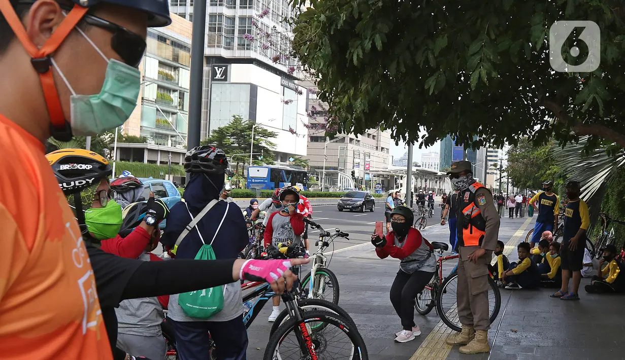 Petugas Satpol PP berjaga di kawasan Bundaran HI, Jakarta, Minggu (3/01/2021).  Aktivitas bersepeda juga masih mendominasi. Tampak 2 lajur di Jl Sudirman menjadi pop up bike line atau jalur sepeda non-permanen, dengan dibatasi cone berwarna oranye. (Liputan6.com/Herman Zakharia)