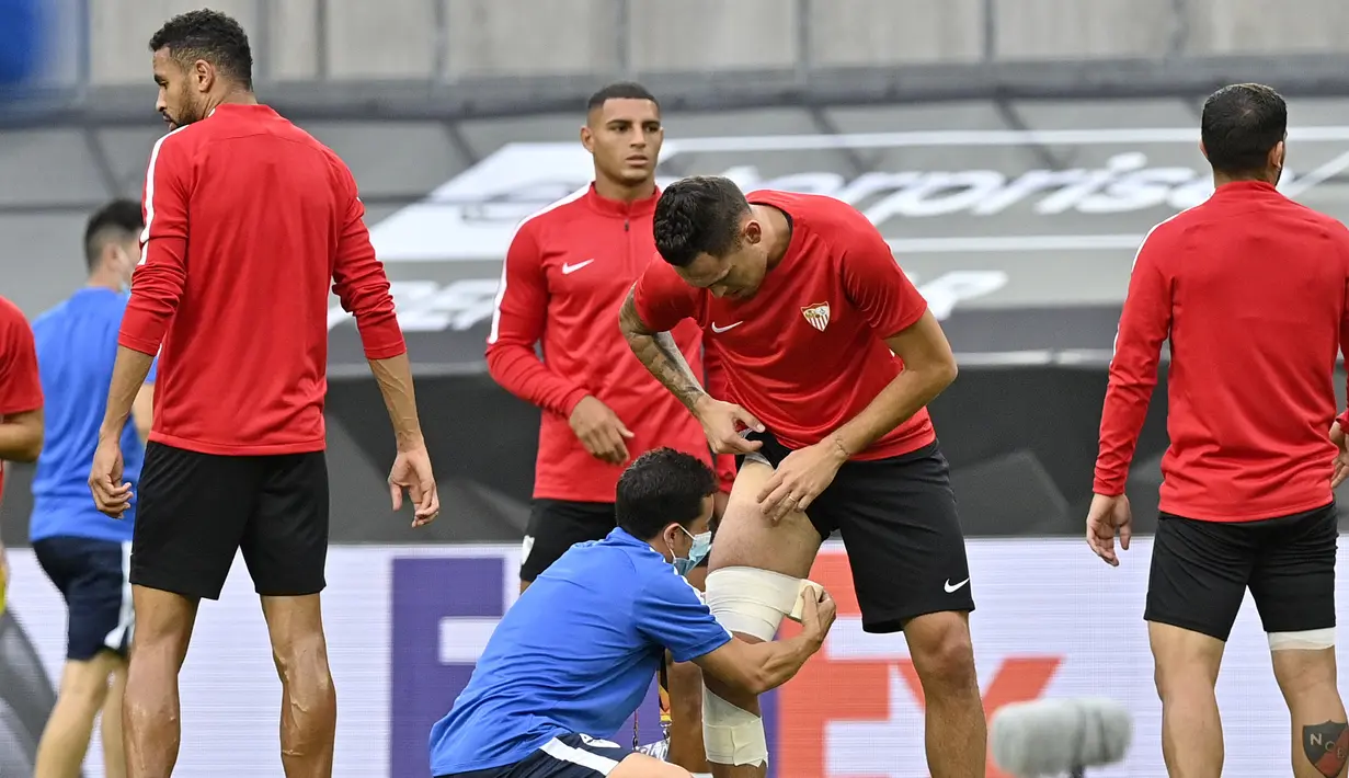 Pemain Sevilla Lucas Ocampos mendapat perawatan saat sesi latihan di Cologne, Jerman, Kamis (20/8/2020). Sevilla akan menghadapi Inter Milan di final Liga Europa. (AP Photo/Martin Meissner)