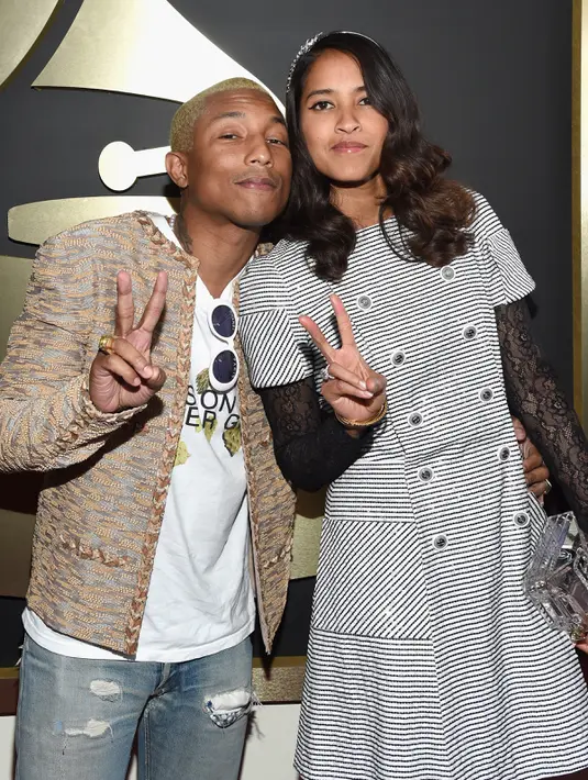 Pharrell Williams dan istrinya, Helen Lasichanh, berpose di karpet merah Grammy Awards 2016 di Los Angeles, Senin (15/2). Sang istri juga tampil modis dalam balutan mini dress putih bergaris. (Larry Busacca/Getty Images for NARAS/AFP)