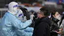 Seorang pria mendapatkan usap tenggorokan untuk tes COVID-19 di fasilitas pengujian virus corona seluler di Beijing, Senin (17/1/2022). Beijing telah melaporkan infeksi omicron lokal pertamanya, beberapa minggu sebelum Olimpiade Musim Dingin akan dimulai. (AP Photo/Andy Wong)