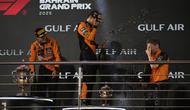 Juara F1 GP Bahrain 2025, Oscar Piastri (kiri), bersama rekan setimnya yang menempati podium ketiga, Lando Norris (tengah), dan team principal McLaren, Andrea Stella, merayakan keberhasilan tim di podium GP Bahrain, di Sirkuit Sakhir, Minggu (13/4/2025) malam WIB. (AP Photo/Altaf Qadri)
