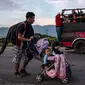 Seorang imigran Honduras mendorong kereta bayi dengan dua anaknya dalam perjalanannya menuju AS di Oaxaca, Meksiko, 29 Oktober 2018. Kereta dorong bayi tak hanya untuk balita mereka, tetapi juga dapat digunakan membawa barang-barang. (Guillermo Arias/AFP)