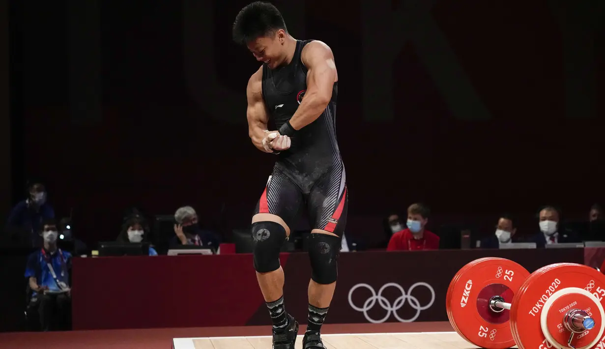 Lifter Indonesia Rahmat Erwin Abdullah menunjukkan ototnya saat berlaga dalam cabang olahraga angkat besi 73 kg putra pada Olimpiade Tokyo 2020 di Tokyo, Jepang, Rabu (28/7/2021). Medali perunggu yang diraih Erwin melebihi target yang diusungnya jelang Olimpiade Tokyo 2020. (AP Photo/Luca Bruno)