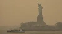 Patung Liberty yang diselimuti langit berkabut difoto dari Staten Island Ferry, New York, Amerika Serikat, Rabu (7/6/2023). New York resmi menjadi kota dengan tingkat udara paling tercemar di dunia, melampaui Kota New Delhi di India. (AP Photo/Yuki Iwamura)