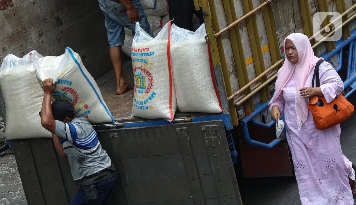 Seorang perempuan melintas dekat aktivitas bongkar muat beras di Pasar Kebayoran Lama, Jakarta, Selasa (26/9/2023). (Liputan6.com/Angga Yuniar)