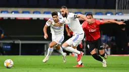 Karim Benzema (tengah) menjadi keran gol Real Madrid saat laga baru berjalan tiga menit. Benzema mampu memanfaatkan kesalahan pemain belakang Mallorca, Josep Gaya dan sukses menaklukkna kiper Manolo Reina. (AFP/Gabriel Bouys)