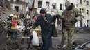 Relawan Pasukan Pertahanan Teritorial Ukraina membantu seorang perempuan menyeberang jalan di Kharkiv, 16 Maret 2022. Invasi Rusia ke Ukraina memasuki hari ke-21. Berbagai upaya negosiasi menuju kompromi telah dilakukan demi menuju perdamaian di antara kedua belah pihak. (AP Photo/Andrew Marienko)