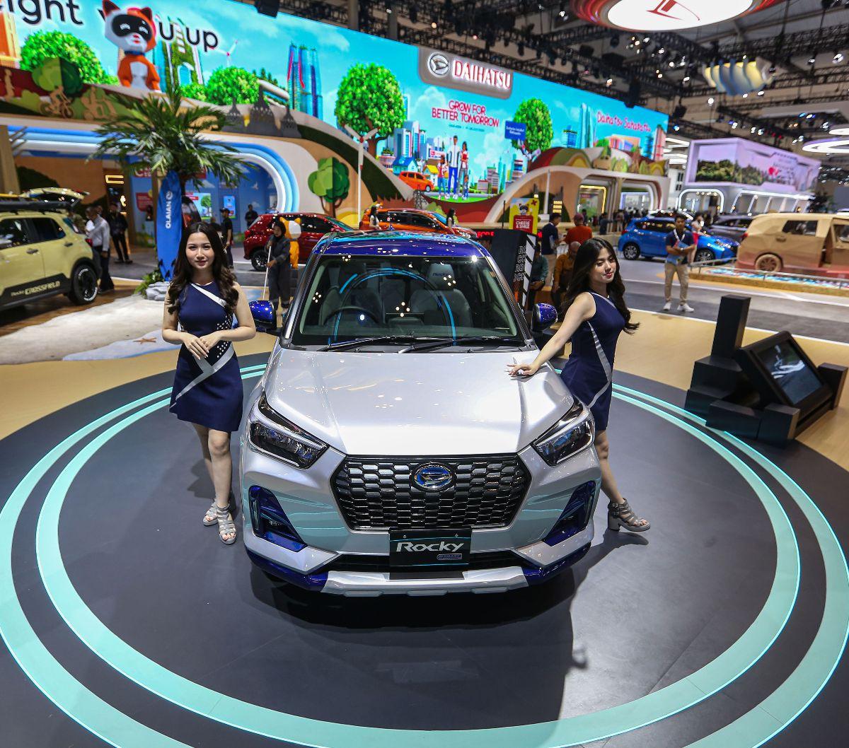 Sales Promotion Girl (SPG) berpose di sebelah Rocky e-Smart Hybrid versi Japan Domestic Market (JDM) pada booth Daihatsu selama pameran Gaikindo Indonesia International Auto Show (GIIAS) 2024 di Indonesia Convention Exhibition (ICE) BSD, Kabupaten Tangera